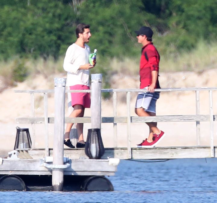 Scott Disick chows down on chips and drink while showing a friend the view from the pier of his house in the Hamptons, NY.