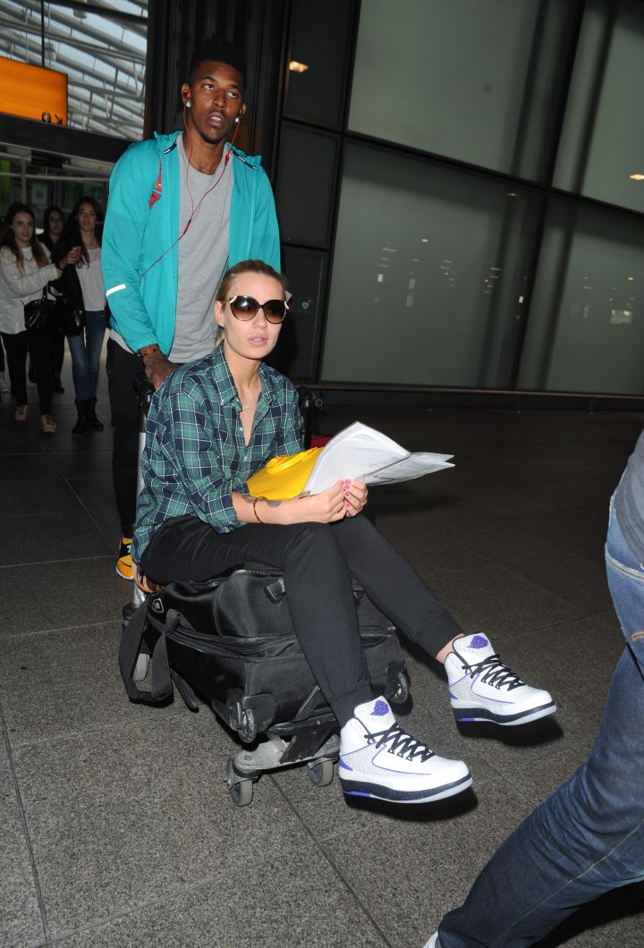 Iggy Azalea is helped by her beau Nick Young through Heathrow.