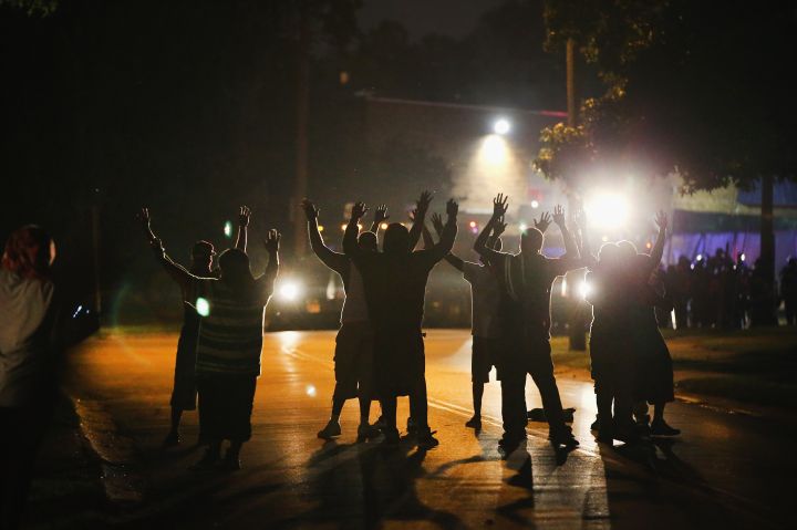 Protestors hold their hands high in the night sky to signify they are unarmed. Michael Brown was unarmed when he was shot by a Ferguson police officer.