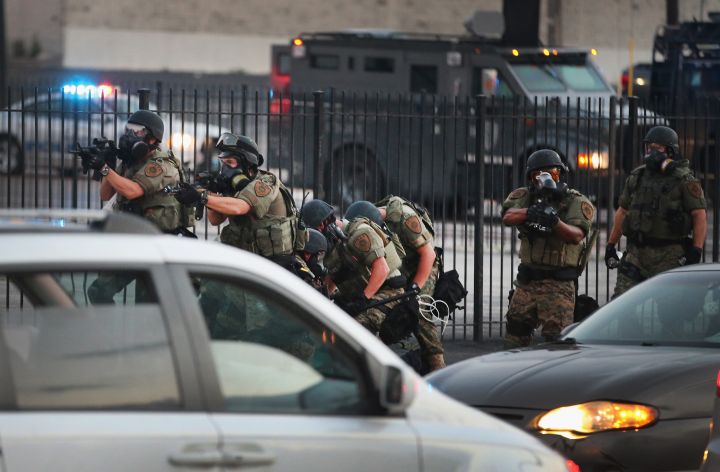 Officers in riot gear advance on protestors.