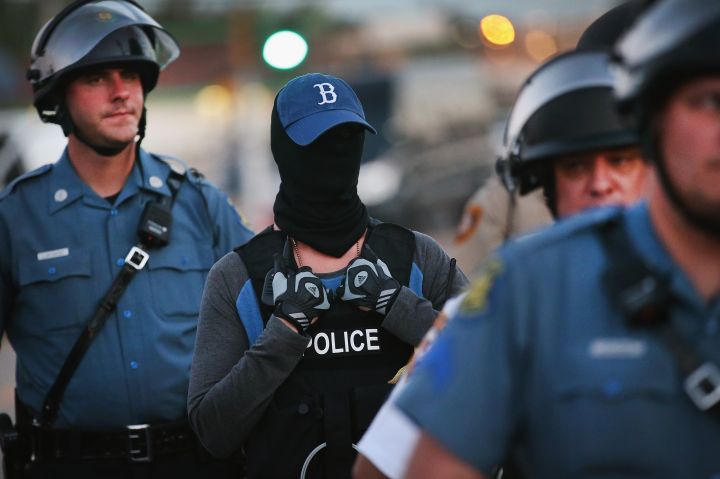 Police officer watches protest concealing his/her identity.
