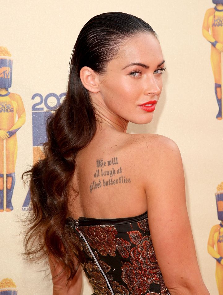 Megan Fox’s tattoo, “We will all laugh at gilded butterflies,” is an adaptation of a quote from King Lear by William Shakespeare.
