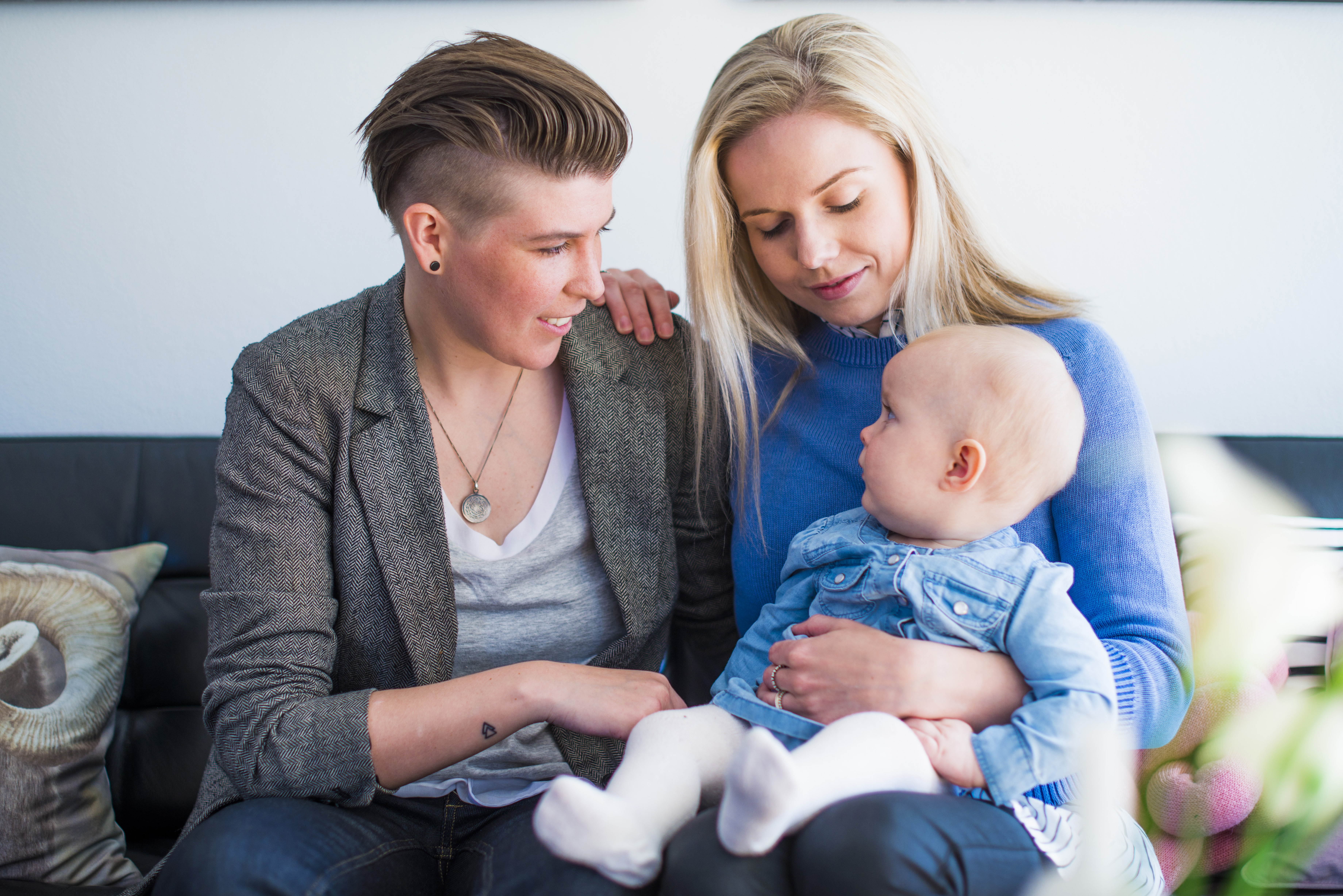 Happy young lesbian couple with baby at home