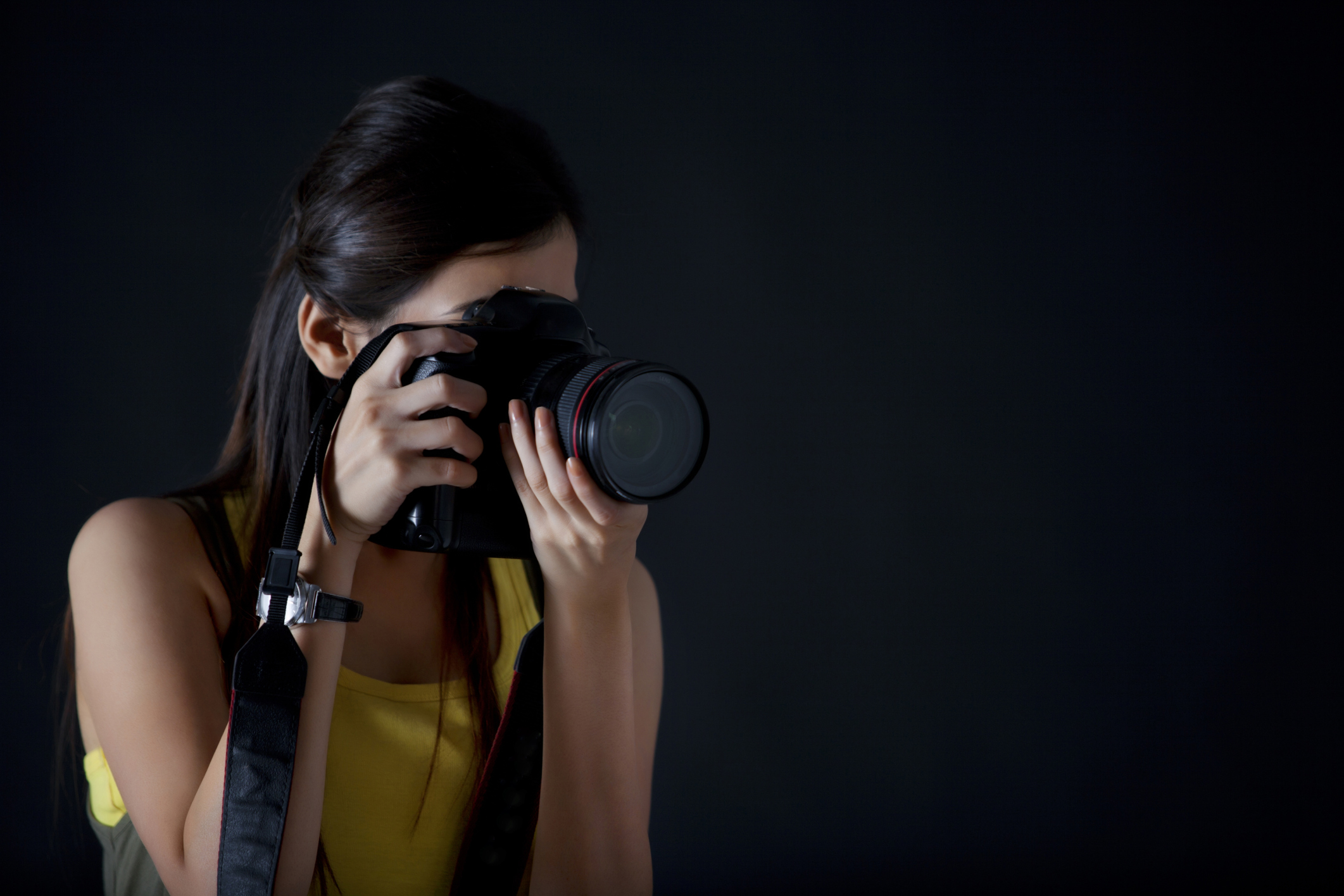 Close-up of young female photographer taking a photograph