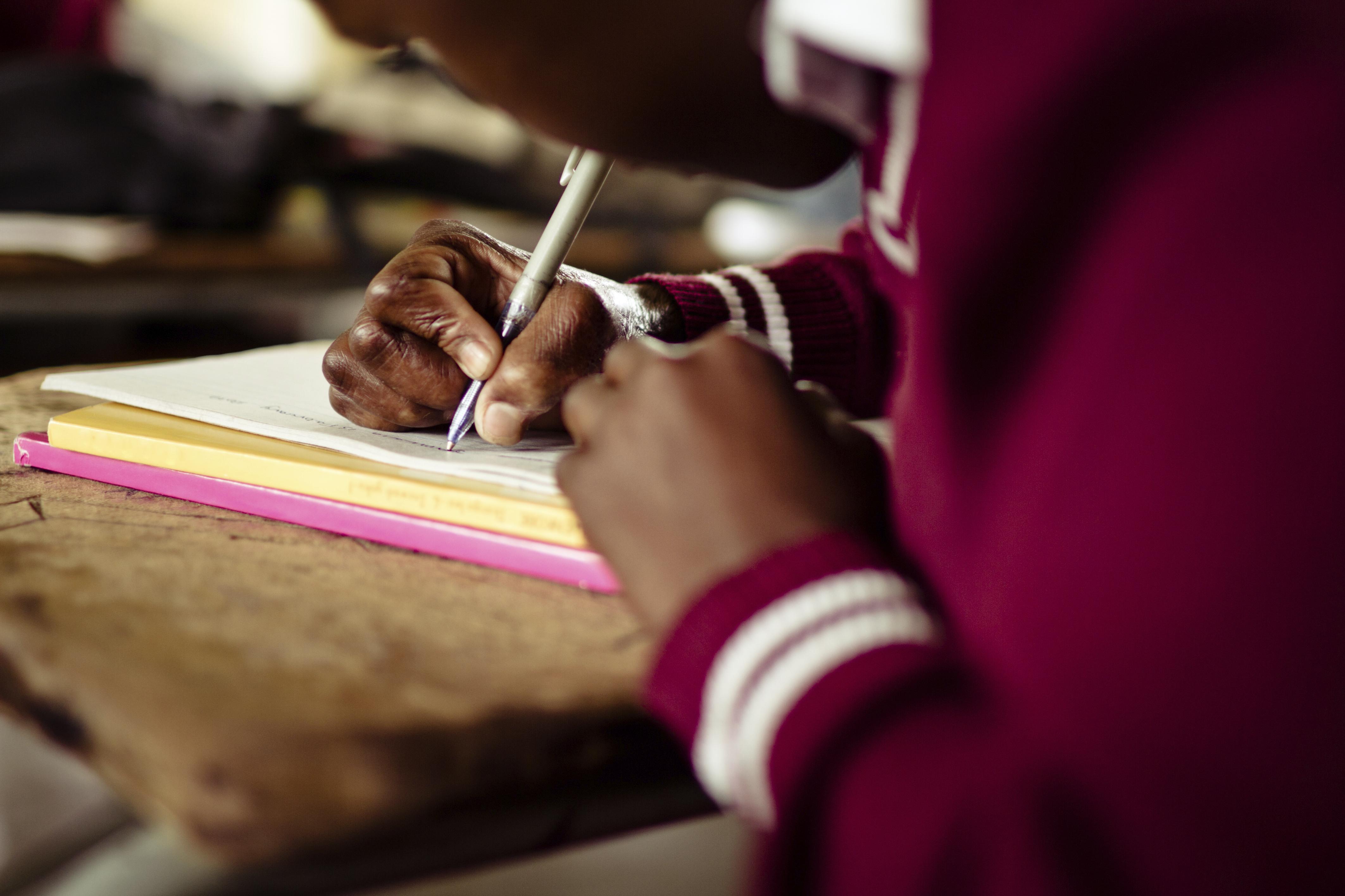 Closeup image of South African girl writing at her desk