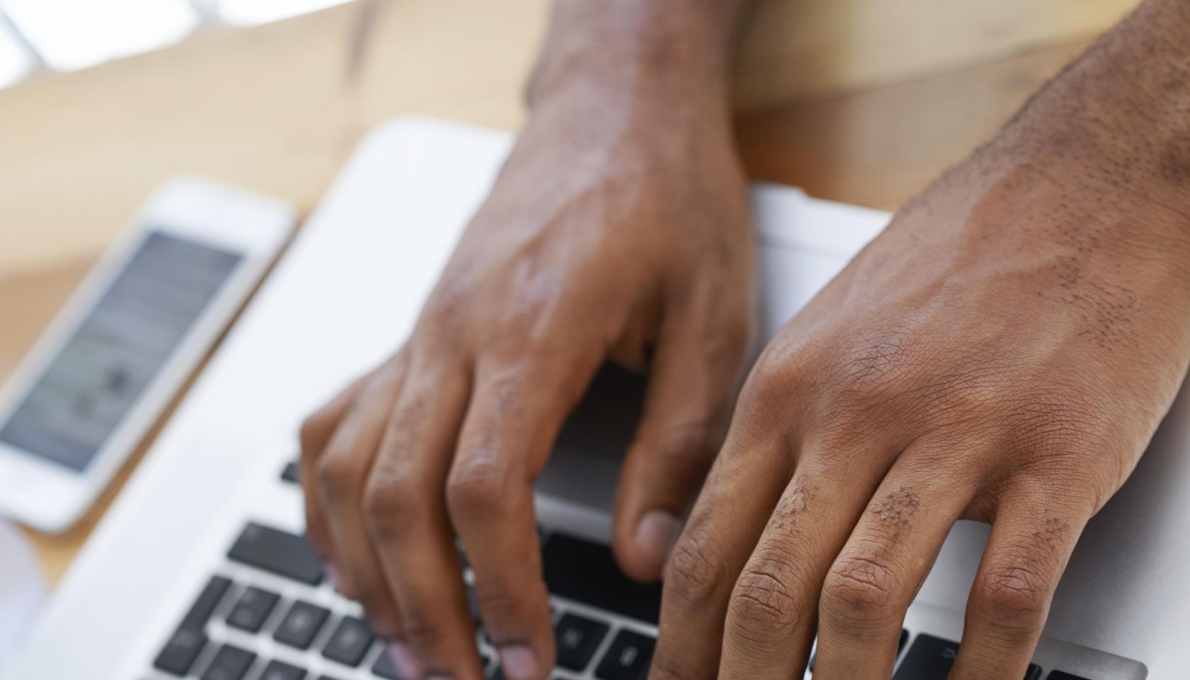 Cropped view of a businessman's hands as he types on his laptop