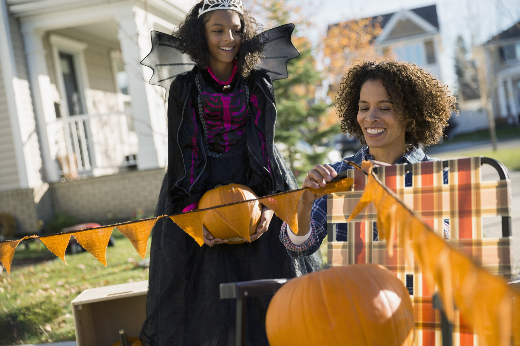 Mother and daughter in Halloween costume decorating yard