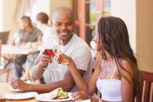 Cheers celebrating and toasting happy african couple having lunch