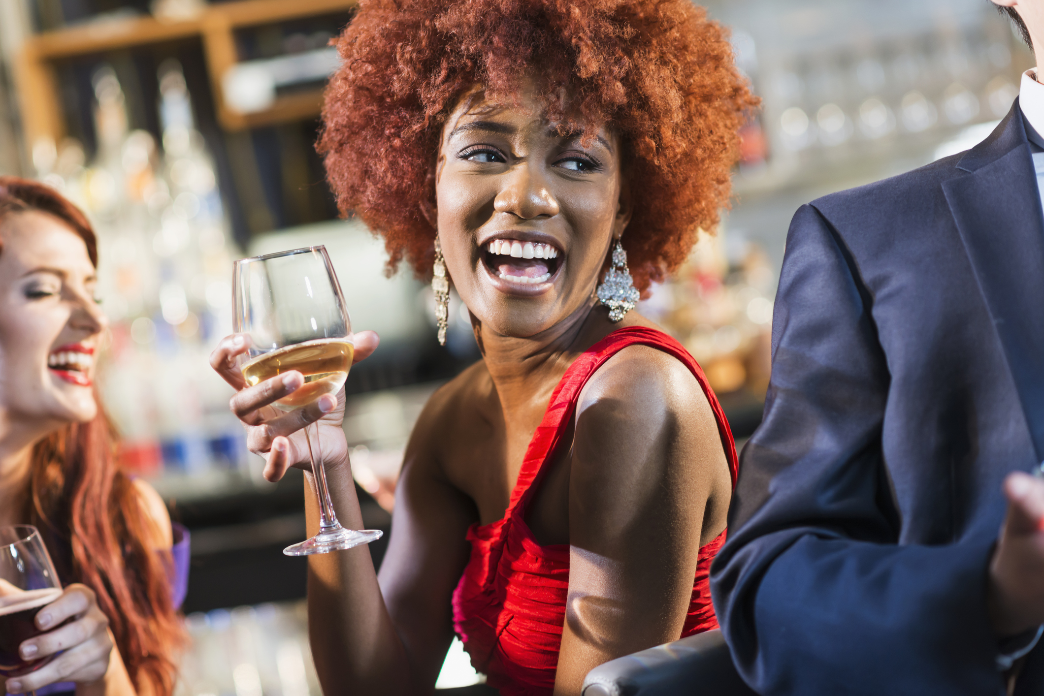 Young black woman in bar drinking, laughing