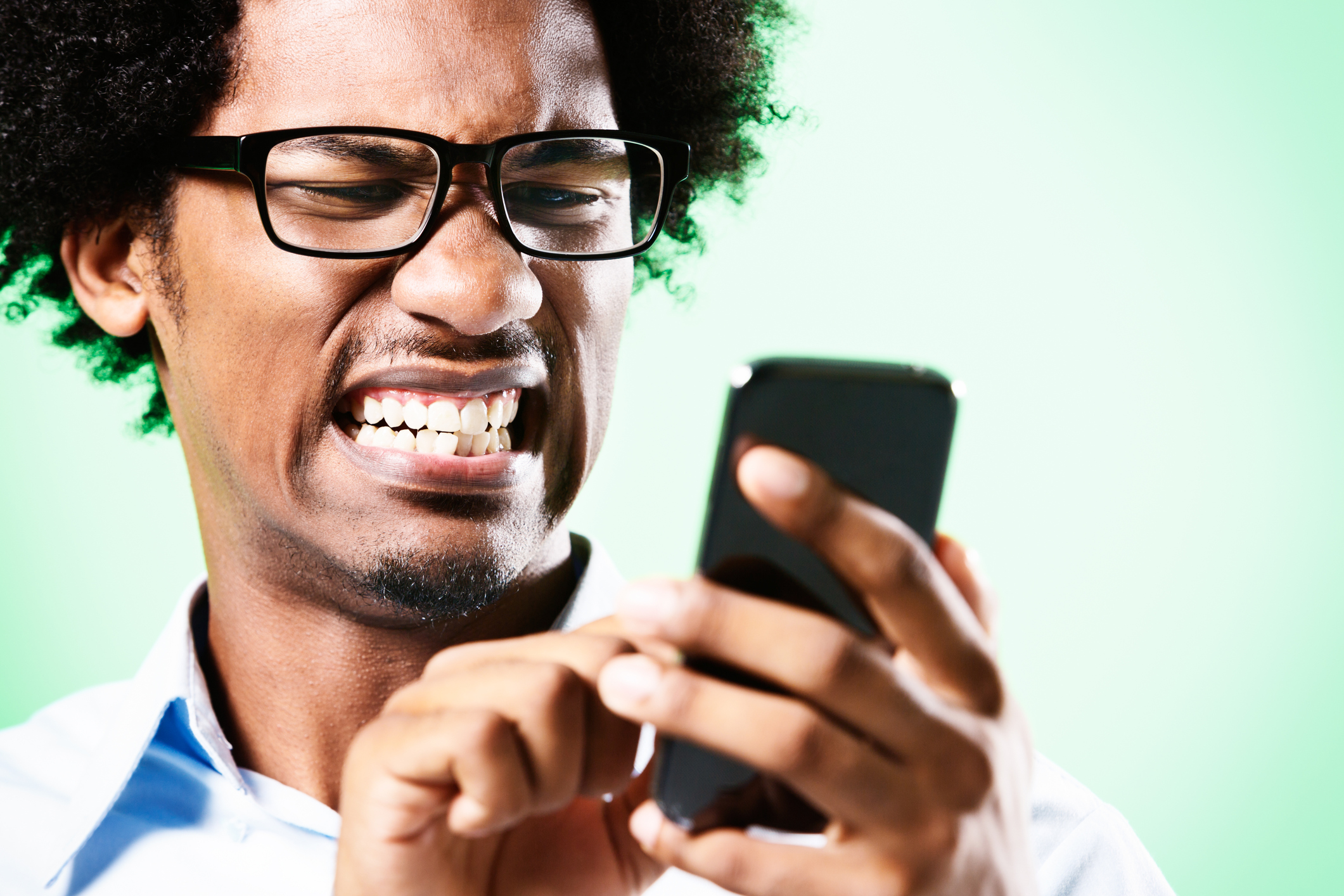 Young afro-haired nerd grimaces at cellphone he holds