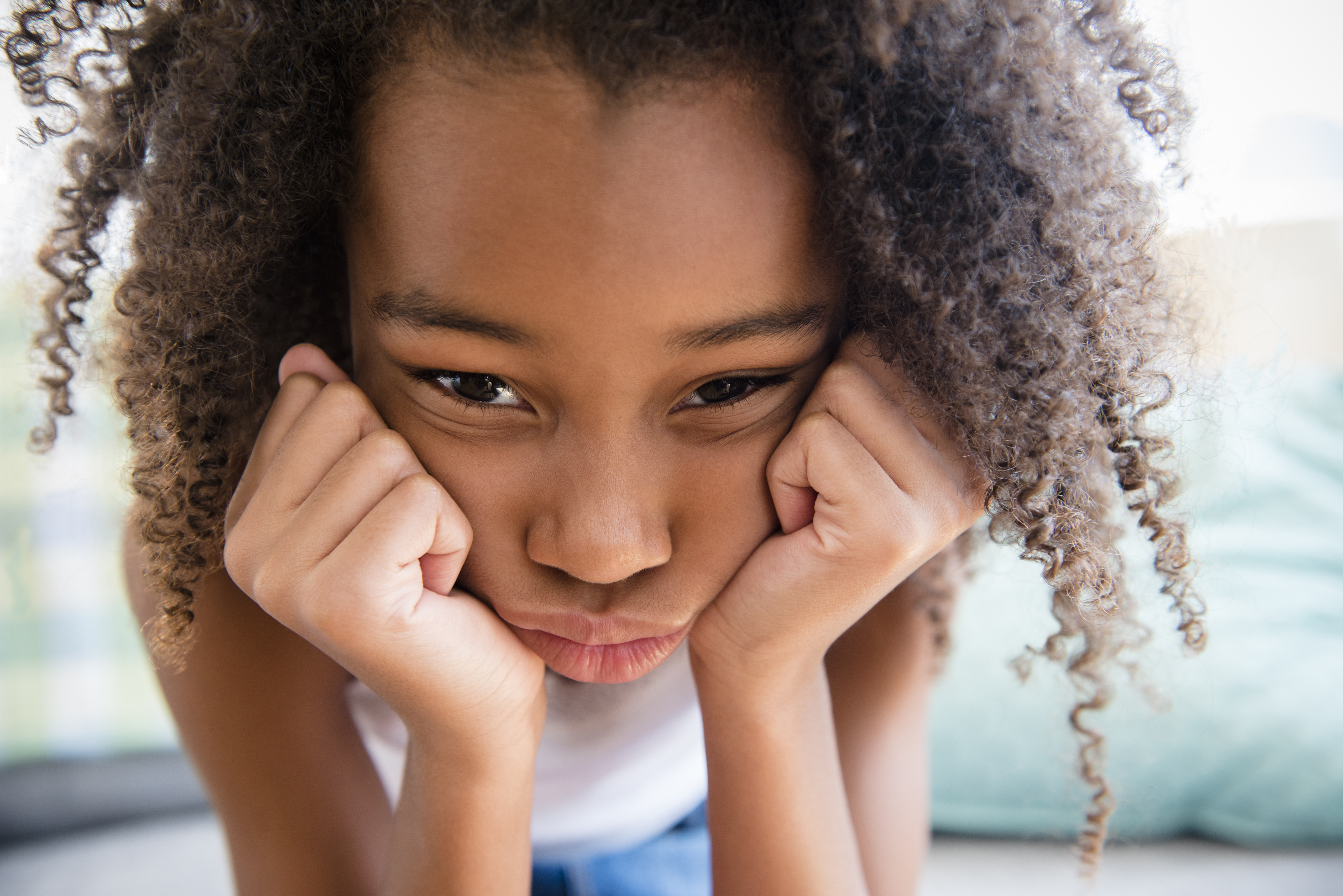 Moody mixed race girl resting chin in hand