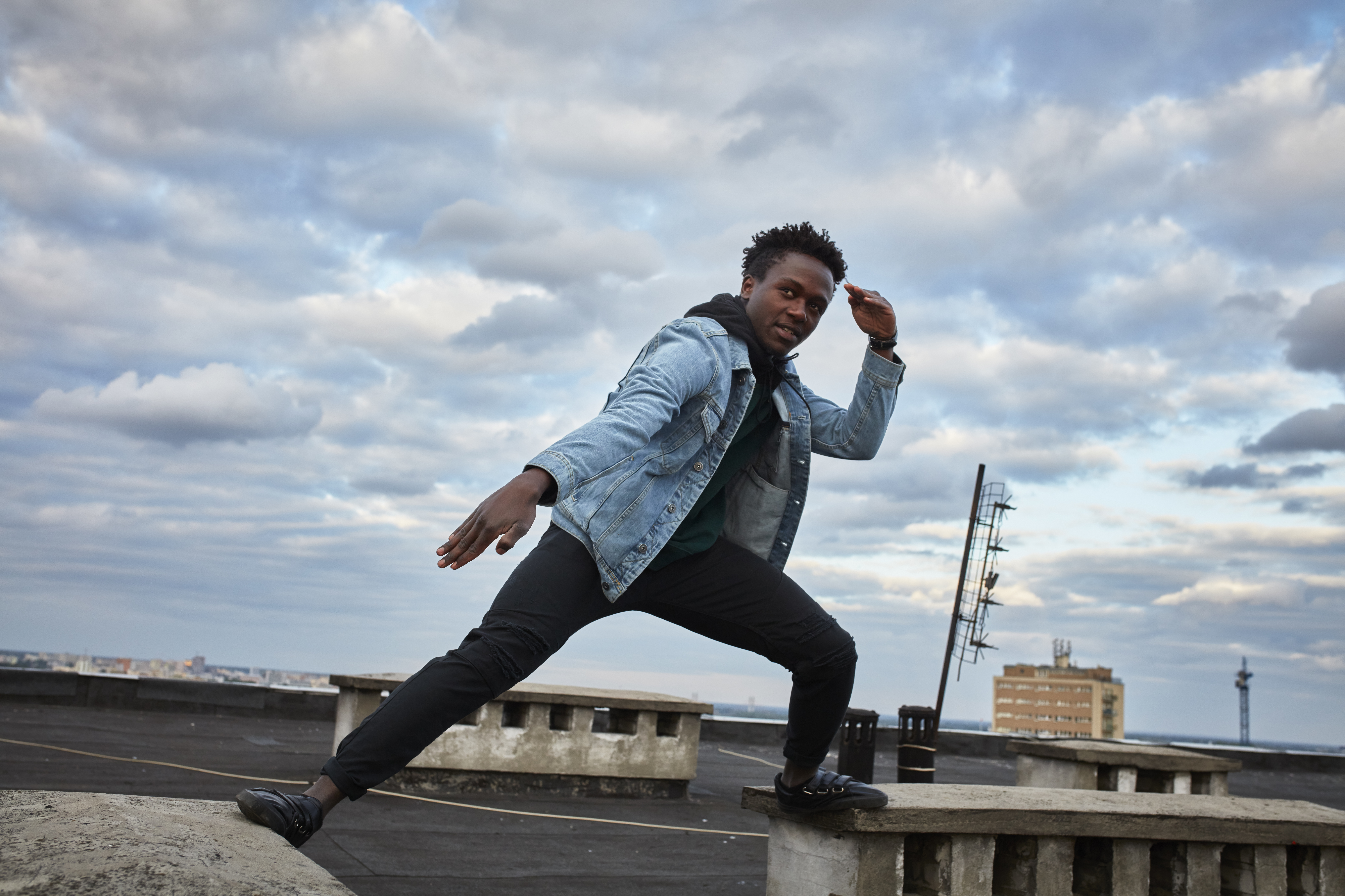 African man catching the wind and dancing on the roof