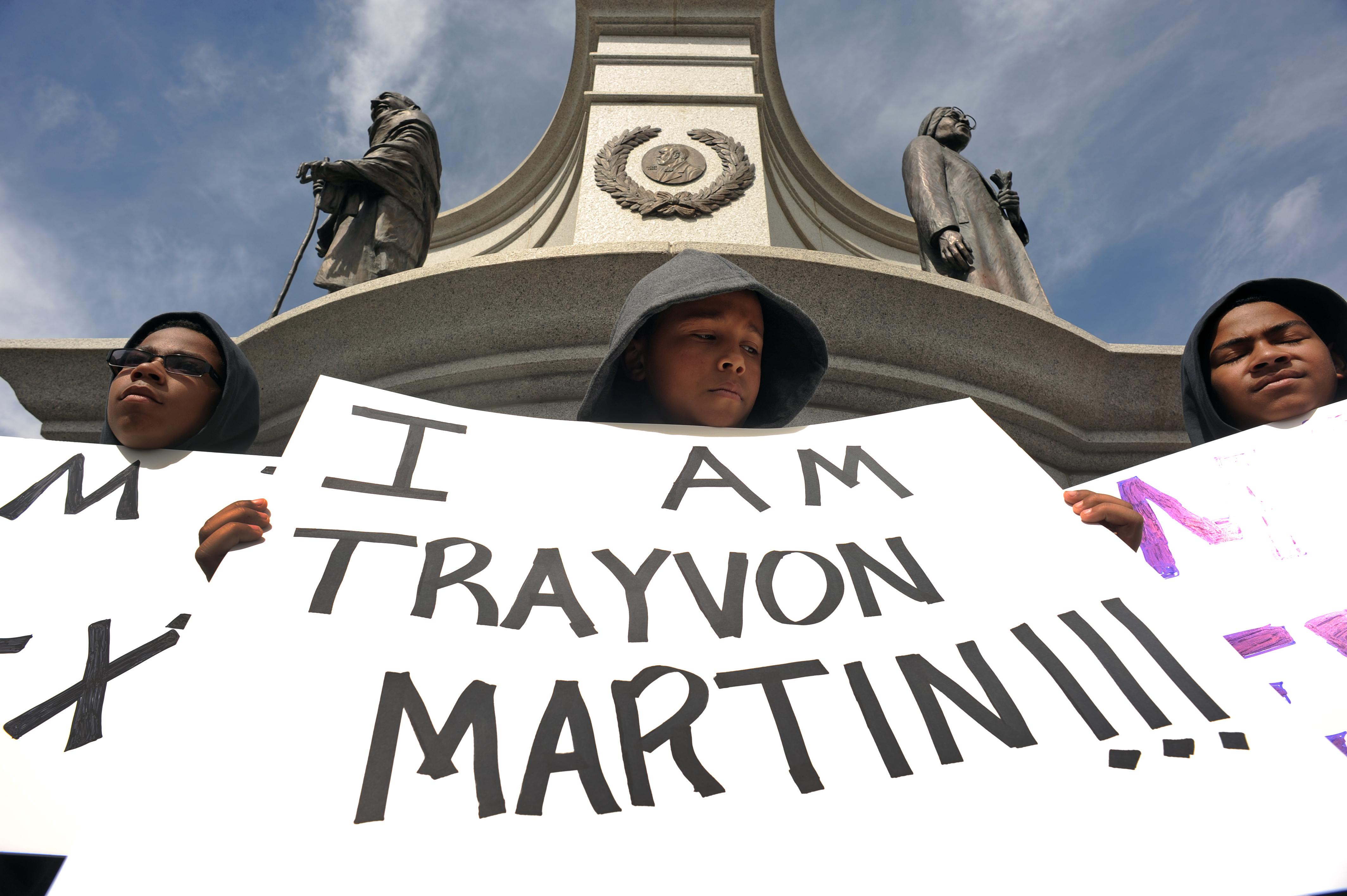 Justice Lindberg, 11, holds a sign during the rally. At left is Noah Spicer, 13, and at right is Mason Spicer, 11. A rally was held in City Park at the Martin Luther King statue today March 25th, 2012. The rally, organized by Community Peace Drummers, was