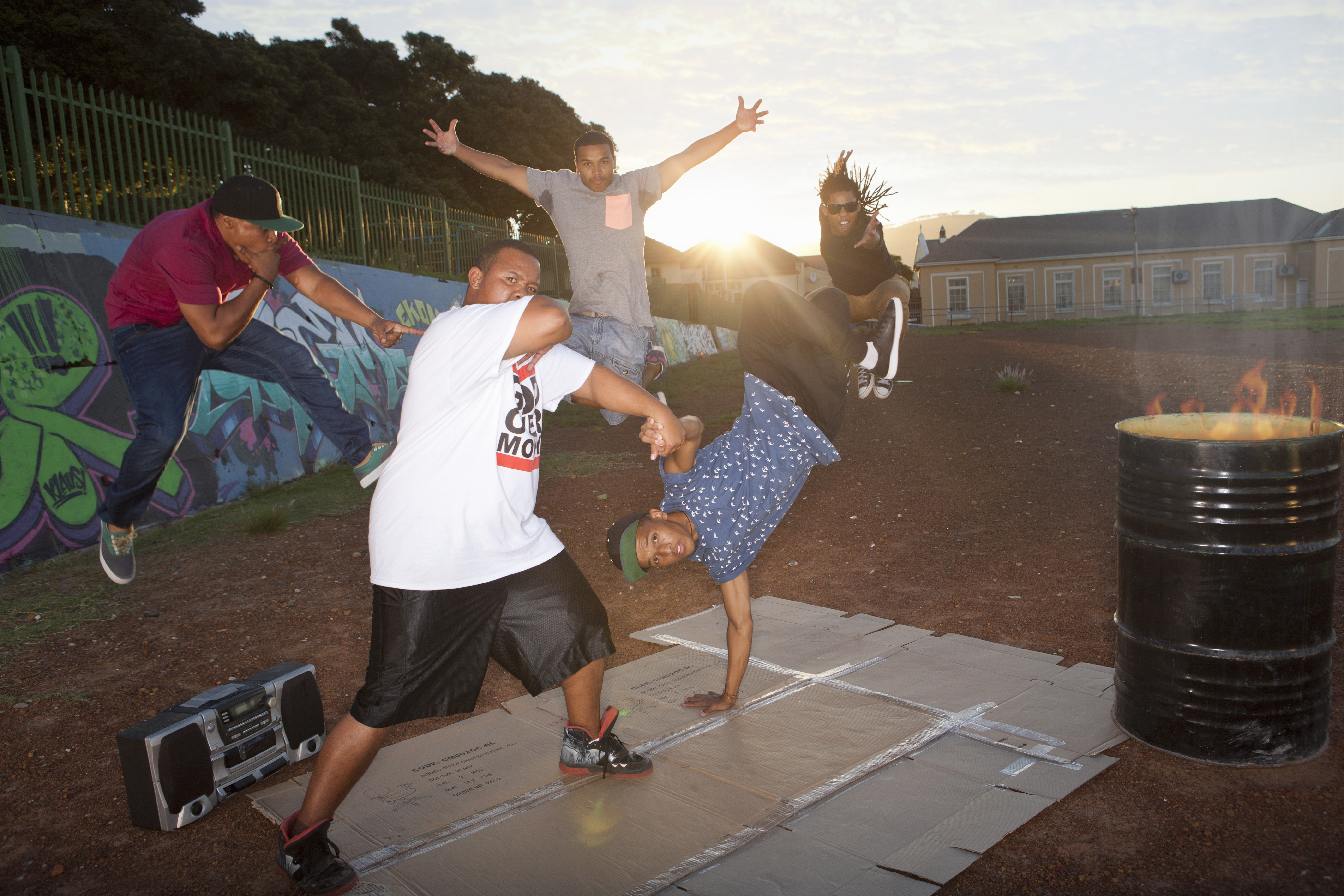 Group of five men breakdancing in park at dusk