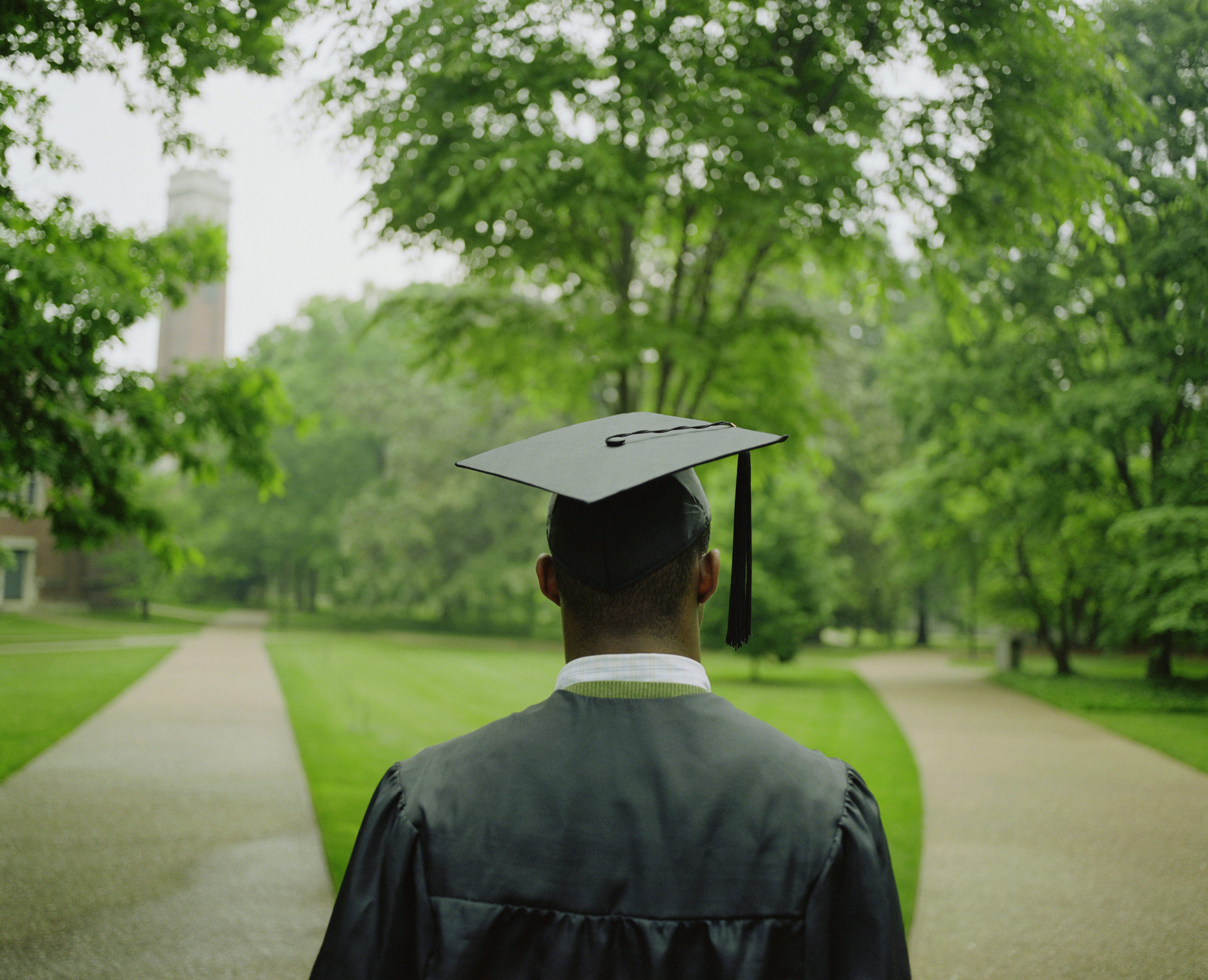 Male college student wearing cap and gown, rear view