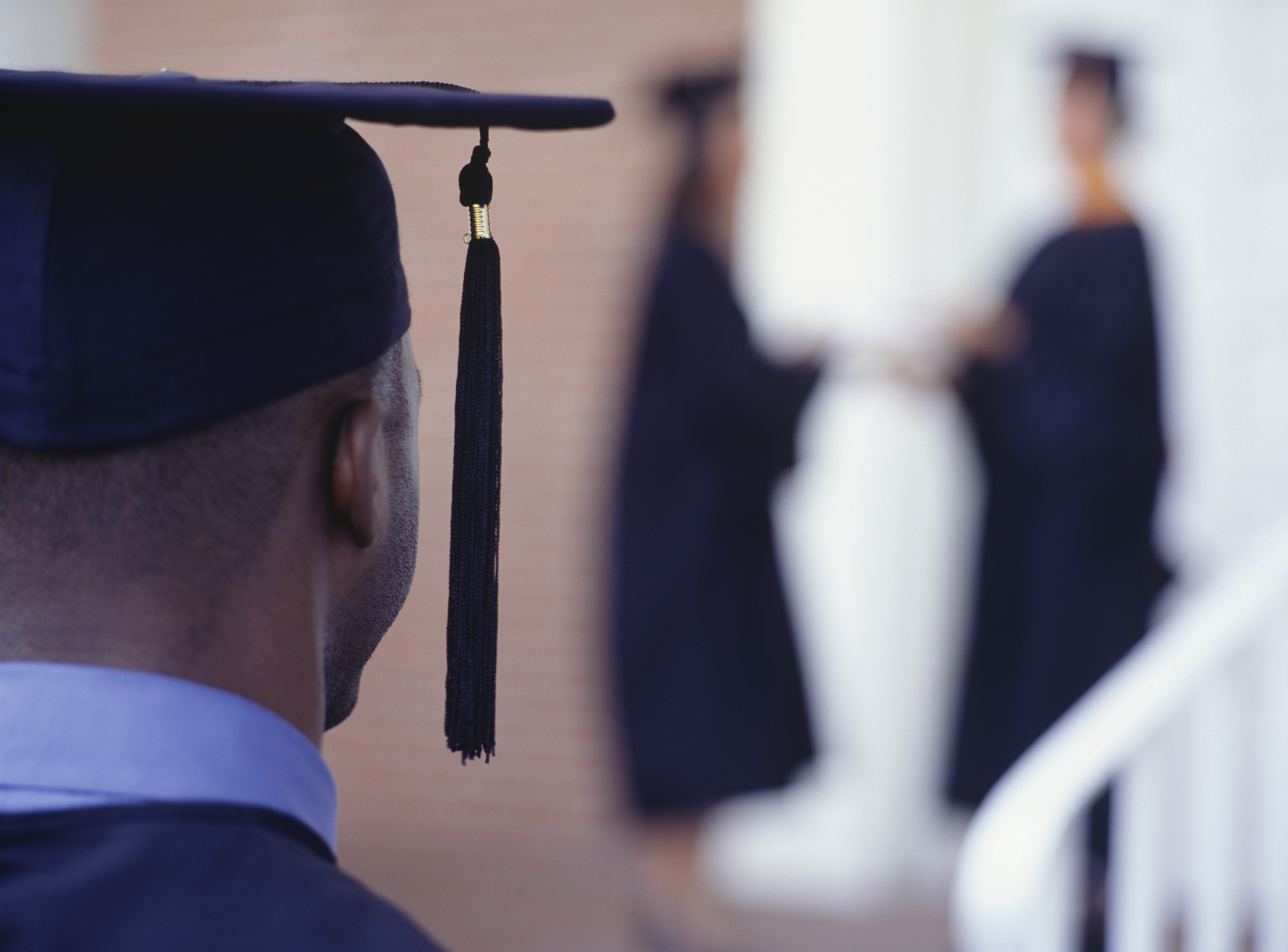 Graduate student watching graduation ceremony, rear view, close-up