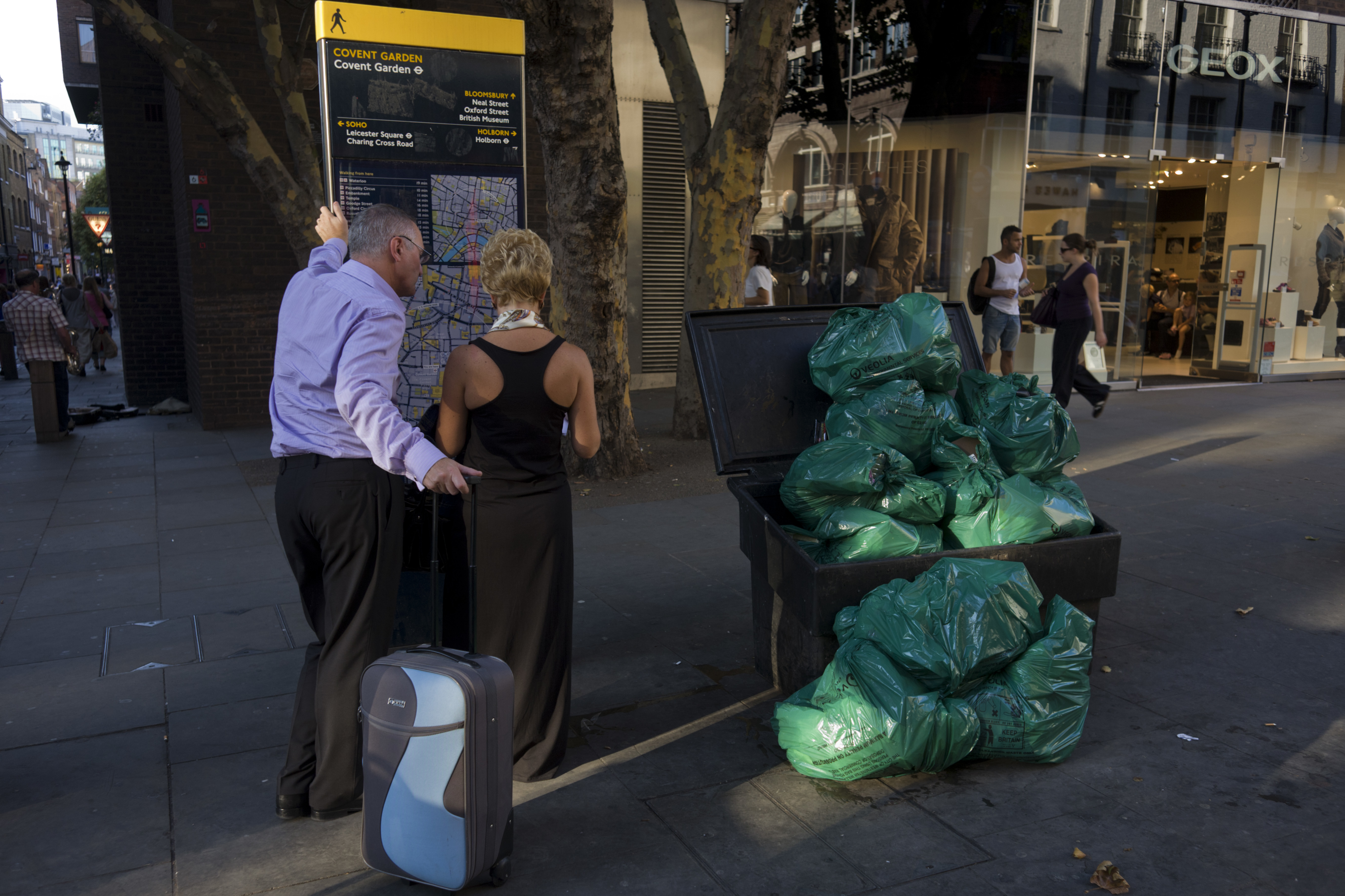 UK - London - Well-dressed couple look at map near rubbish