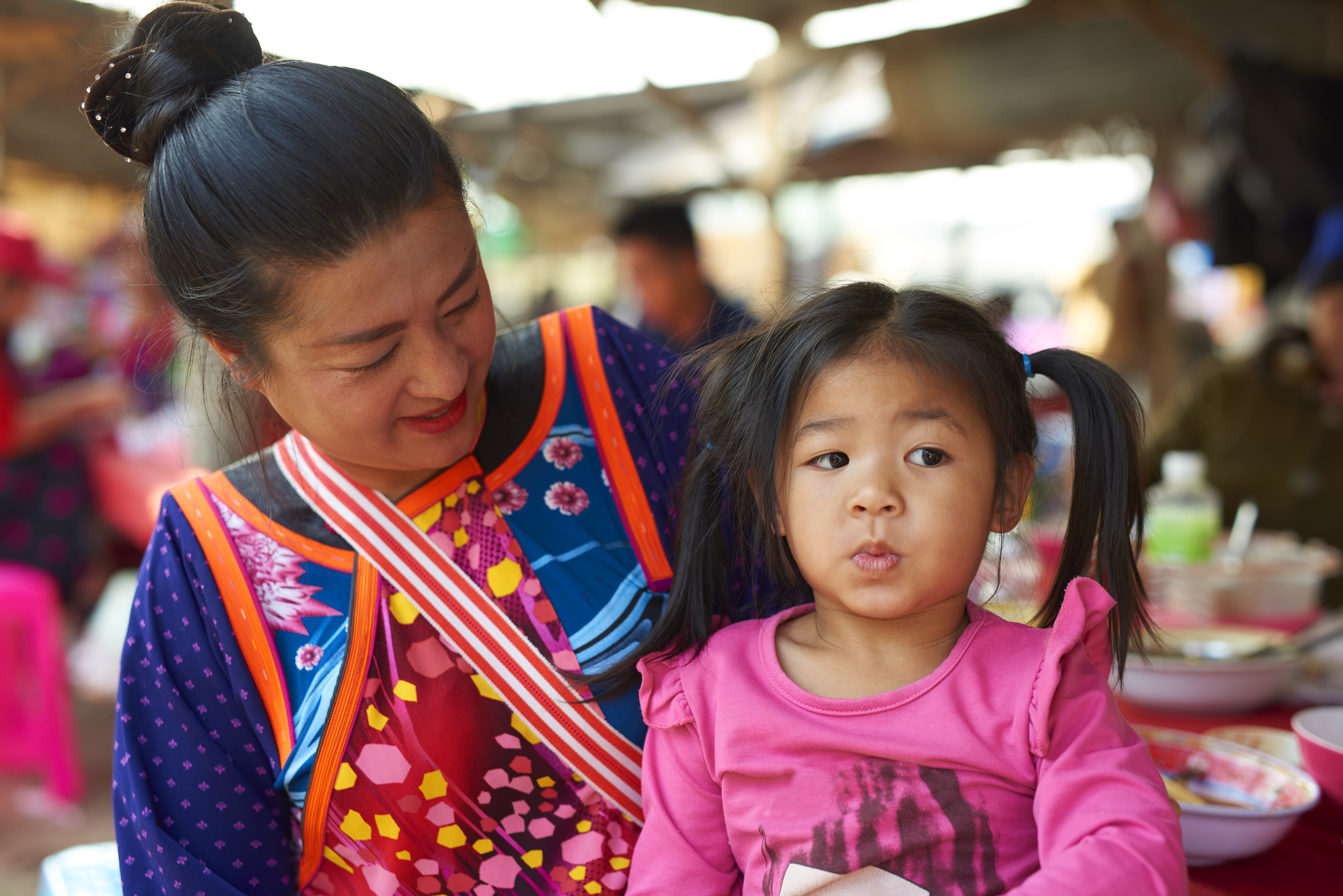 A child sits on her mother's lap as mum looks on in adoration