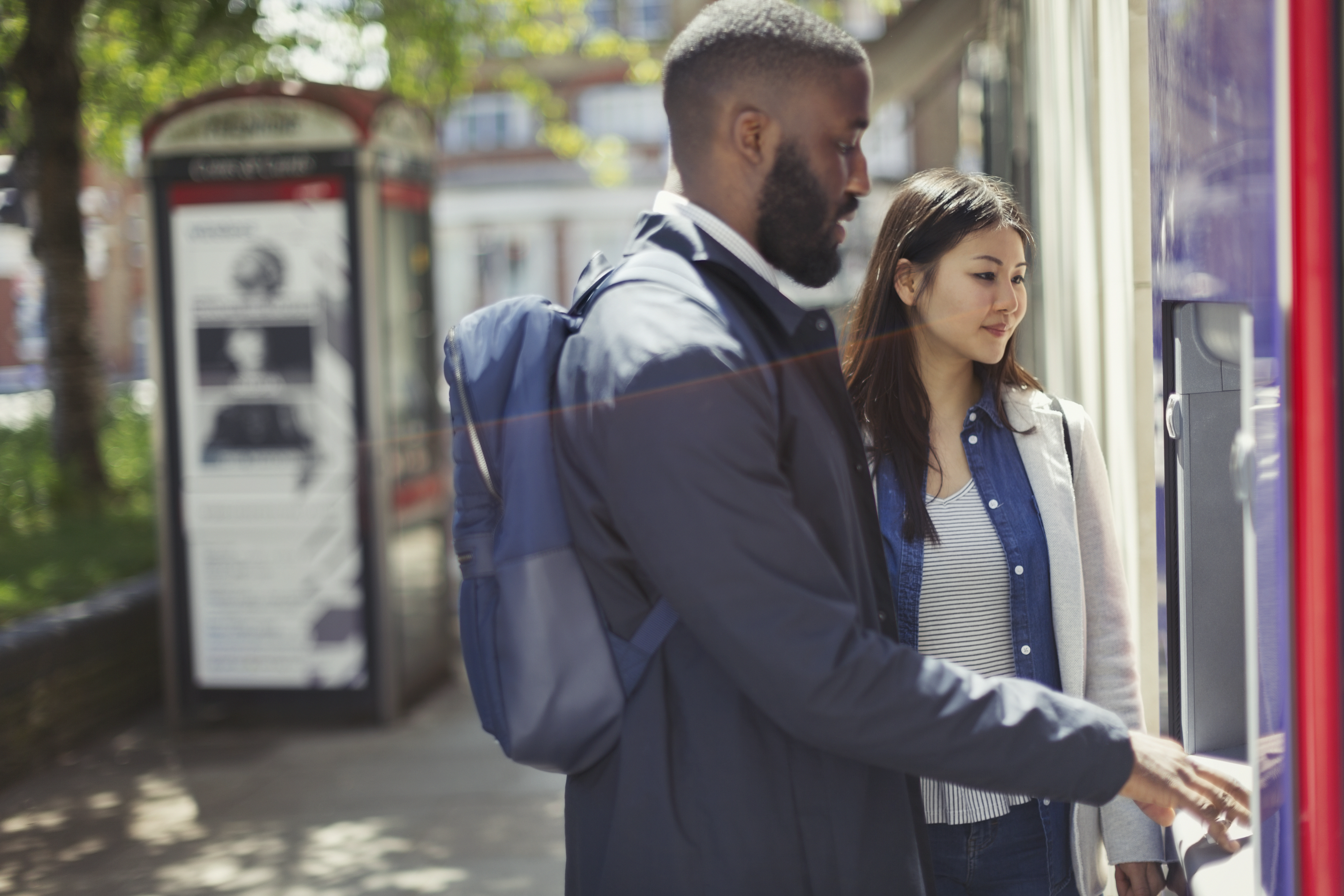 Young couple using urban ATM