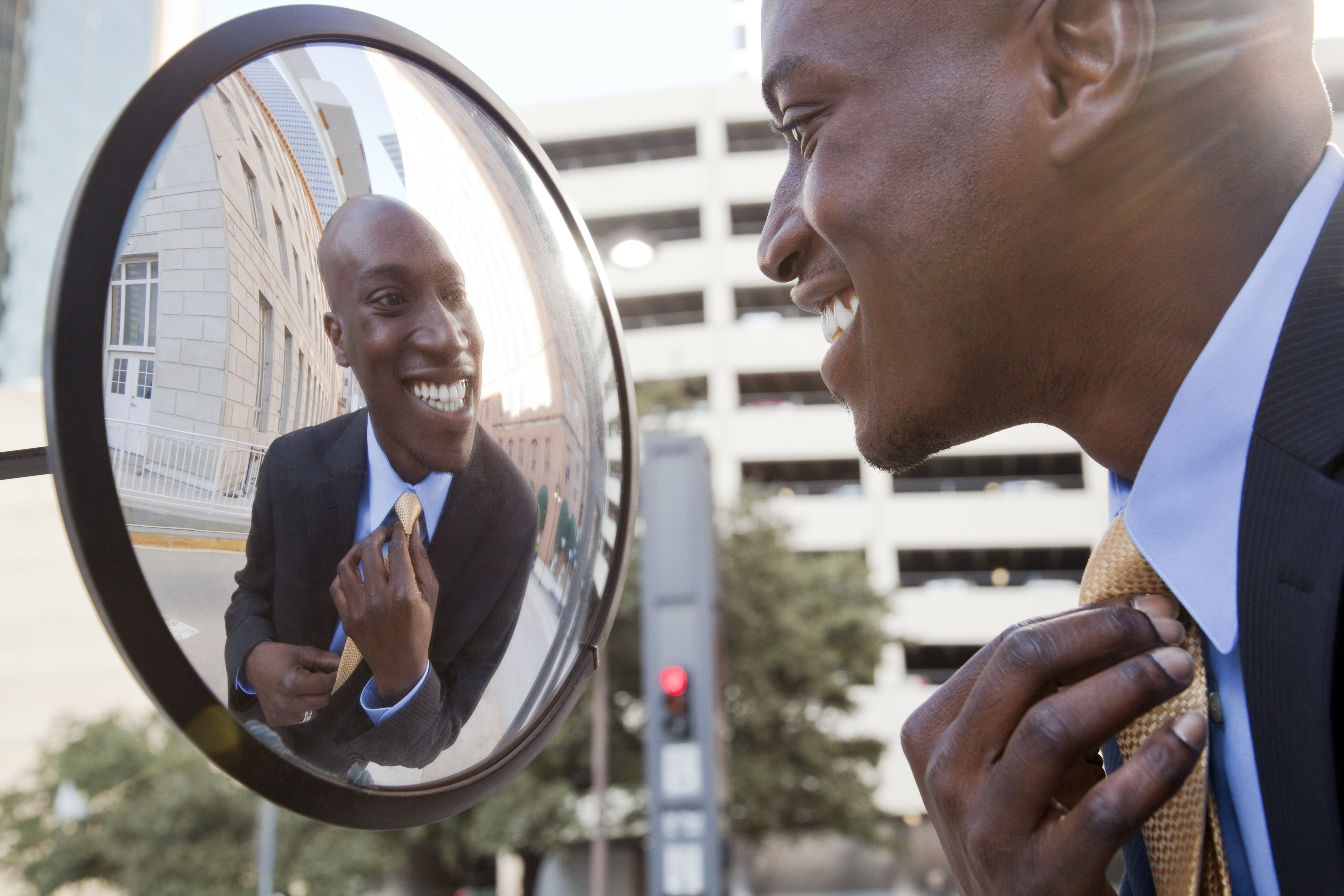 African American businessman adjusting tie in mirror