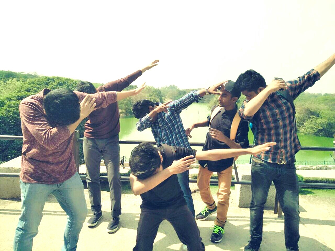 Friends Performing On Bridge Over River Against Clear Sky
