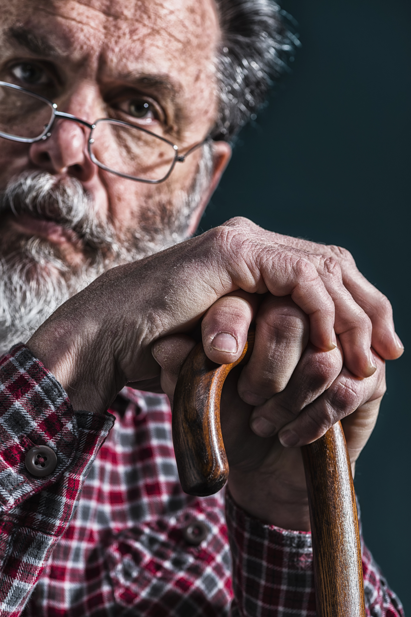 Close-up of old man's arthritic hands on cane