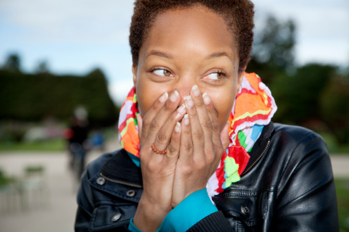 Woman laughing, hands cover mouth.