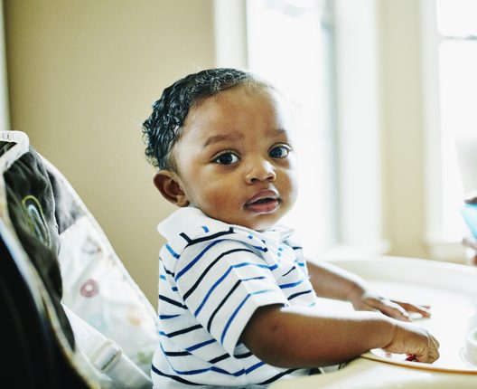 Infant boy sitting in highchair during breakfast