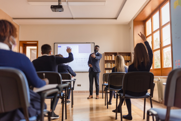 High school teacher giving a lecture, using smart board
