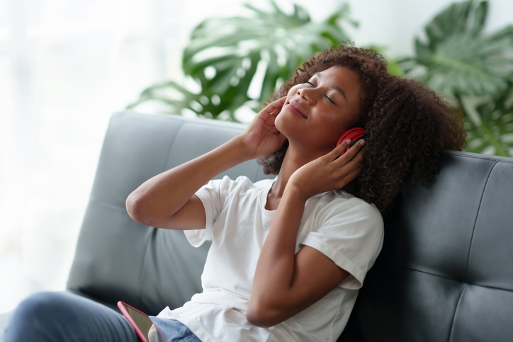 Young women are cute and charming and bright, wearing headphones, listening to music happily, enjoying listening to music at home in their free time on vacation.