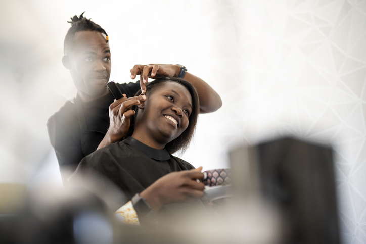 Hairdresser shown finished detail of hairstyle to client