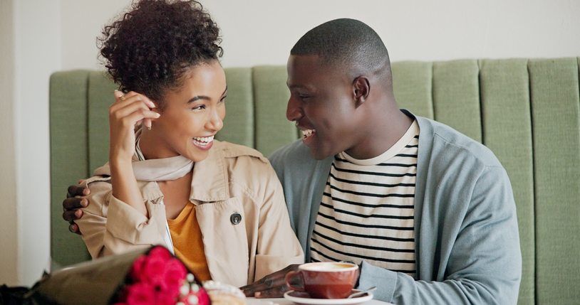 Laugh, love or happy couple hug at coffee shop to relax on romantic anniversary or morning date. Smile, interracial or people bonding at cafe, breakfast or restaurant for drinking cappuccino together