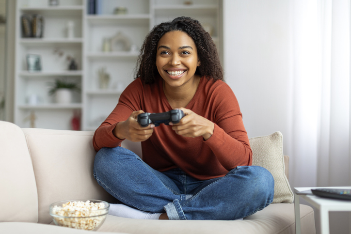 Domestic Fun. Cheerful Young Black Woman Playing Video Games At Home