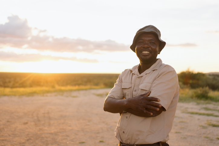Smiling safari guide posing at sunset in the african savanna